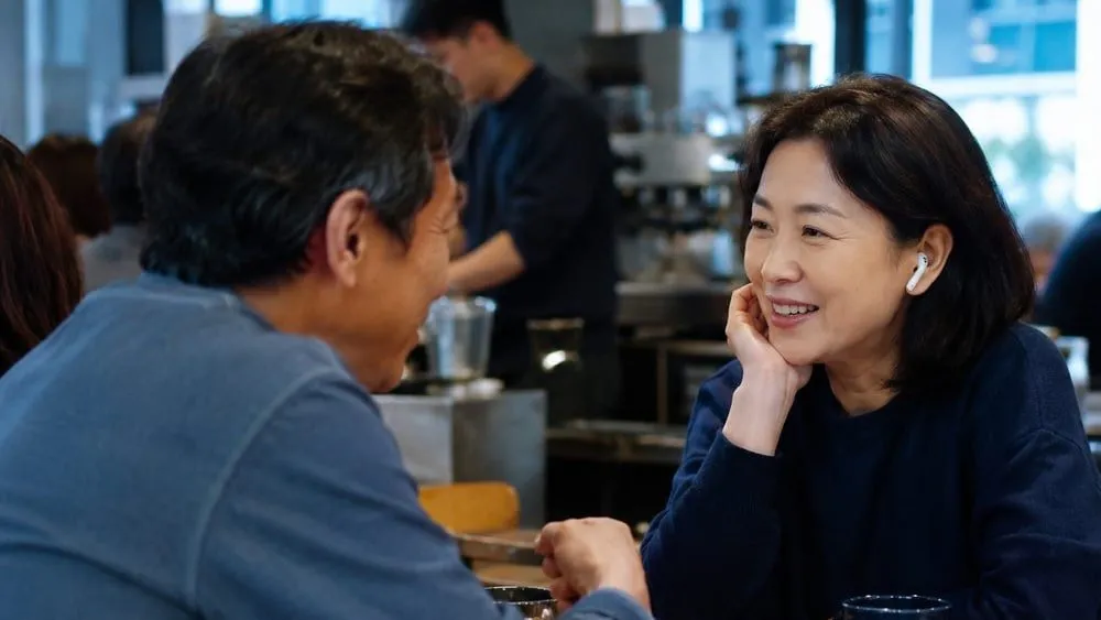 붐비는 카페에서 주변 소음 속에 마주 앉아 대화하는 두 사람